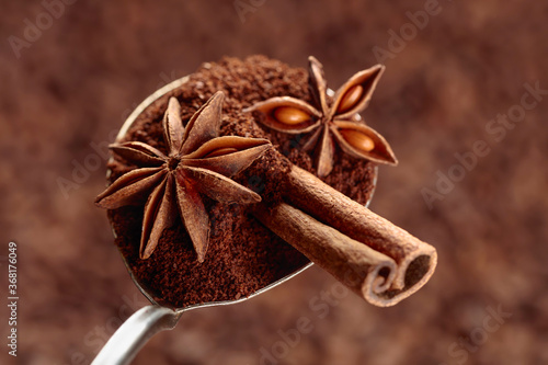 Spoon of ground coffee with anise and cinnamon on the background of coffee beans.