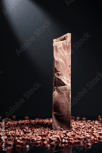 Large piece of dark chocolate and falling chocolate crumbs.