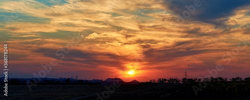 sunset with multicolored clouds in the sky in the summer field. panorama banner