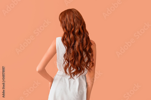 Beautiful young redhead woman on color background, back view
