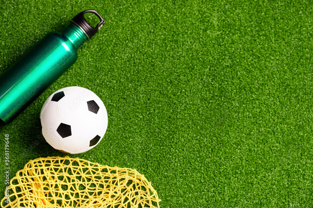 Obraz premium Soccer ball, bottle of water and net on green field