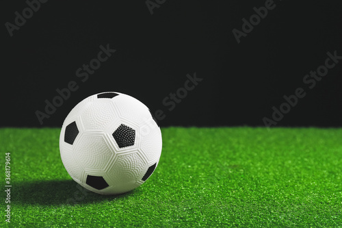 Soccer ball on green field against dark background © Pixel-Shot