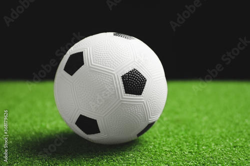 Soccer ball on green field against dark background © Pixel-Shot