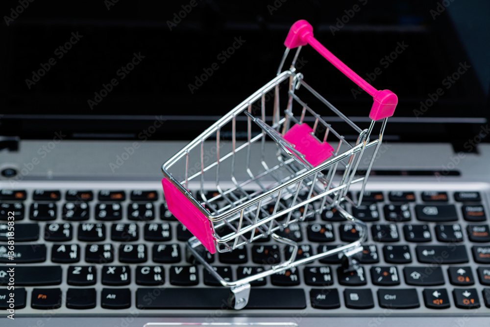 Shopping cart or supermarket trolley with laptop notebook, e-commerce and online shopping concept.