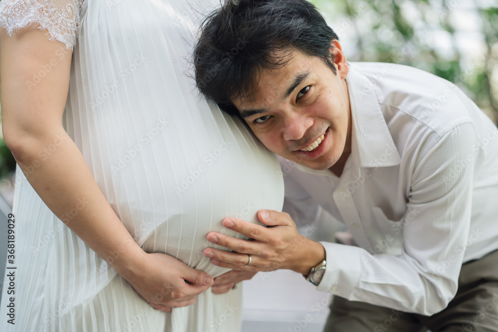 The middle-aged Asian man was proud of his first child and wife. He held hands, listened to the sound, touched the reaction with the child. The middle-aged Asian man was proud of his first child and wife. He held hands, listened to the sound, touched the reaction with the child.