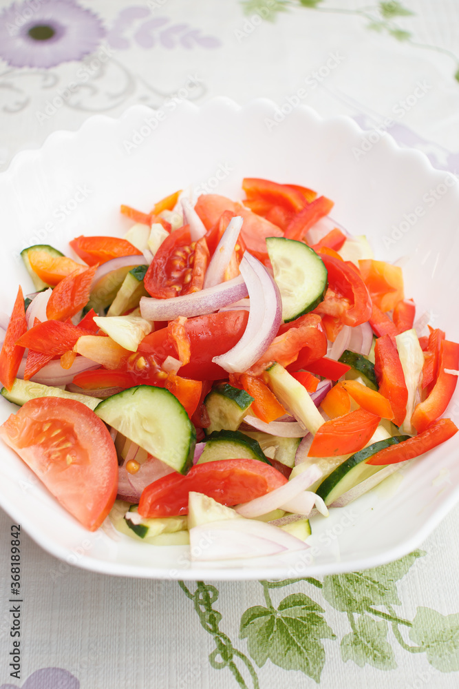 Vegetarian food. Salad of tomatoes, cucumbers, sweet peppers and onions drizzled with vegetable oil. Salad in a white plate.