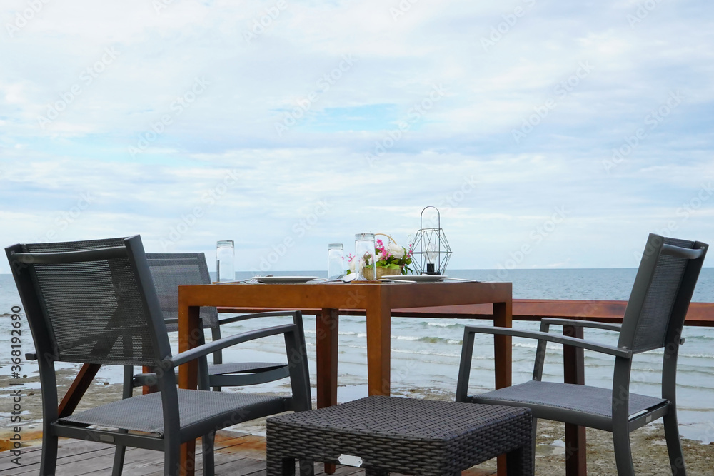 Dinner setup table on terrace nearby the sea with clear blue sky.