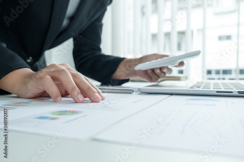 The hands of a male businesswoman use the calculator are analyzing and calculating the annual income and expenses in a financial graph that shows results To summarize balances overall in office