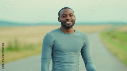 Portrait smiling young handsome africn american man look to camera stand on road enjoying independent face natural happy summer slow motion photo