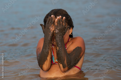 girl in the water with dirty hands on her face 