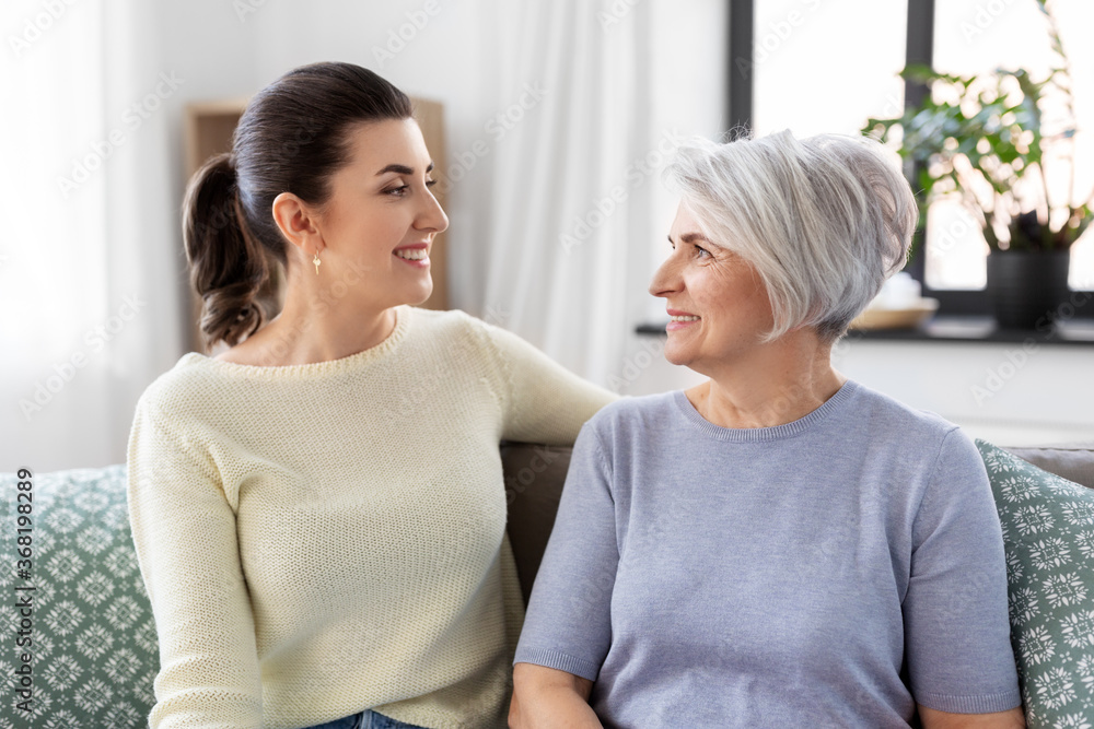 family, generation and people concept - happy smiling senior mother with adult daughter talking at home family, generation and people concept - happy smiling senior mother with adult daughter talking at home