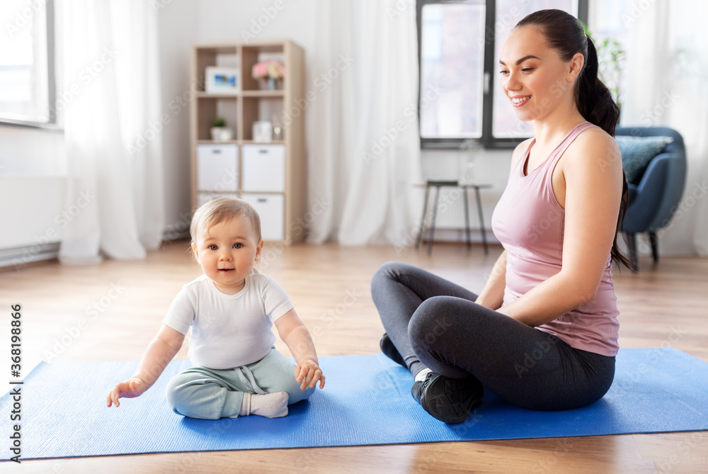 family, sport and motherhood concept - happy smiling mother with little baby sitting on exercise mat at home family, sport and motherhood concept - happy smiling mother with little baby sitting on exercise mat at home