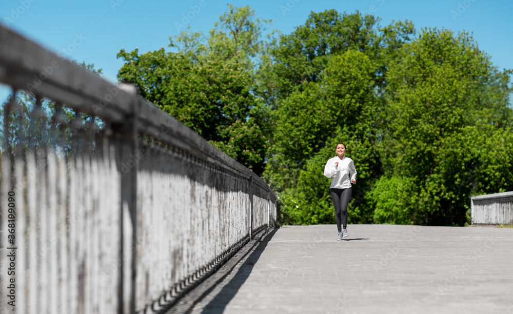 fitness, sport and healthy lifestyle concept - happy smiling young african american woman running outdoors fitness, sport and healthy lifestyle concept - happy smiling young african american woman running outdoors