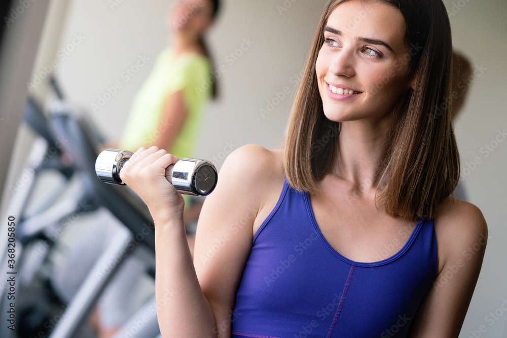 Young beautiful woman doing exercises with dumbbell in gym Young beautiful woman doing exercises with dumbbell in gym