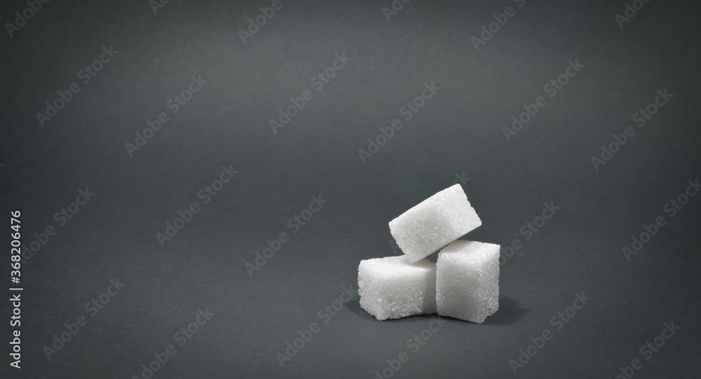 White cubes of sugar on a black background. source of glucose. A sweet addition to tea. White cubes of sugar on a black background. source of glucose. A sweet addition to tea.