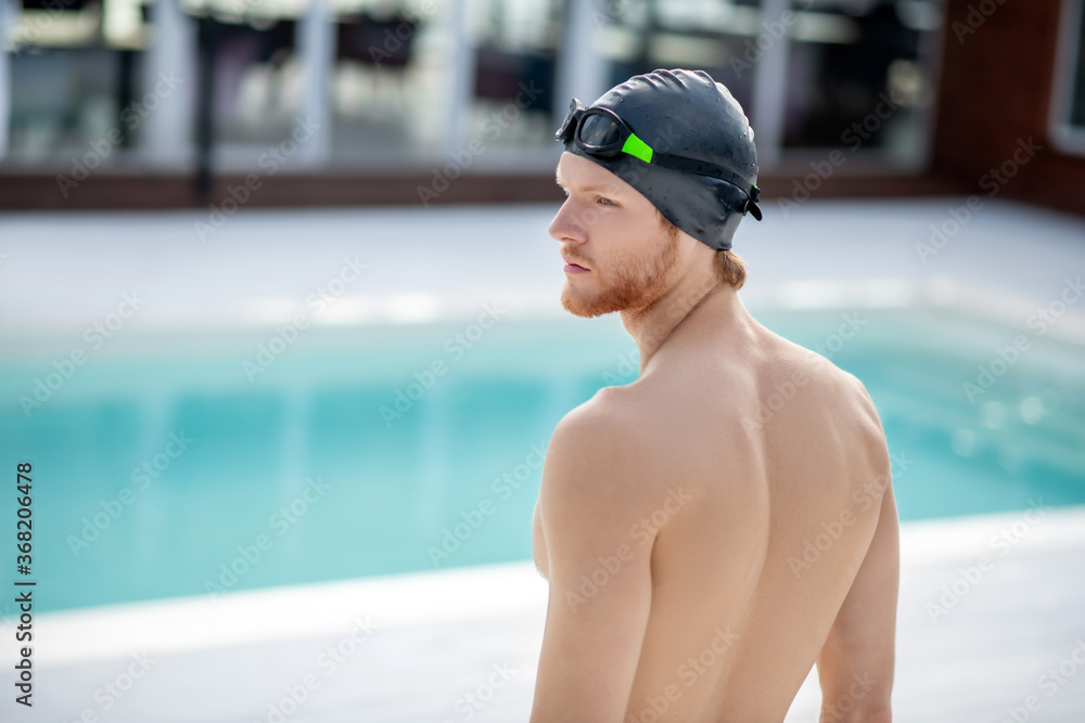 Guy in swimming cap standing in front of pool