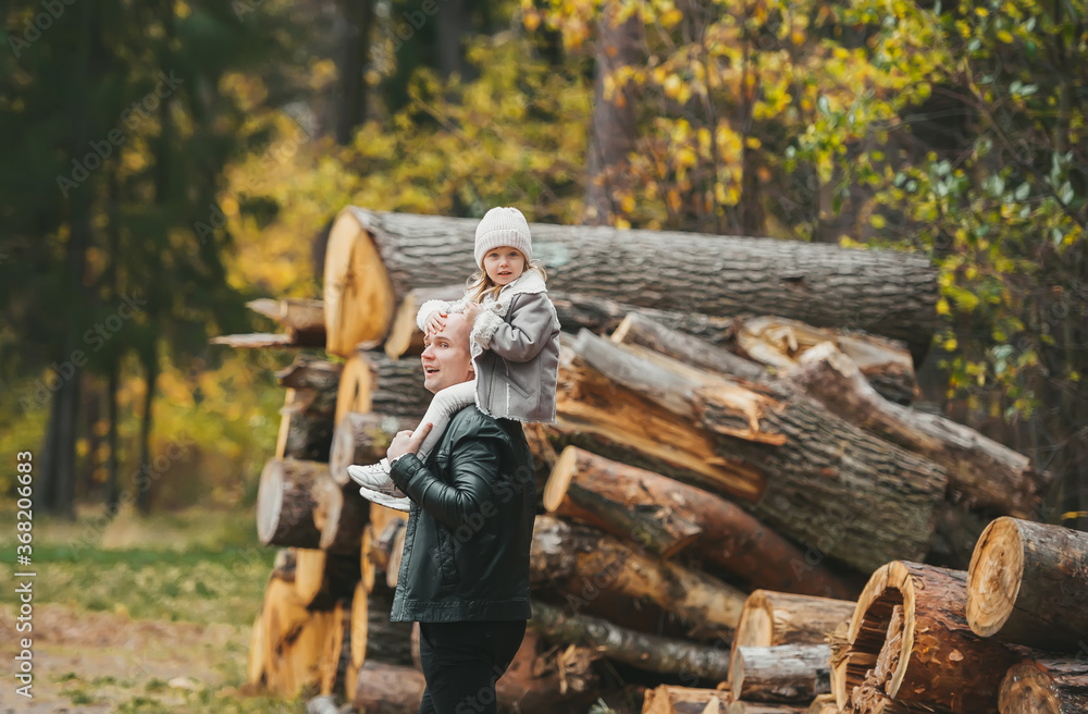A handsome father and his small daughter having fun in autumn forest. A handsome father and his small daughter having fun in autumn forest.