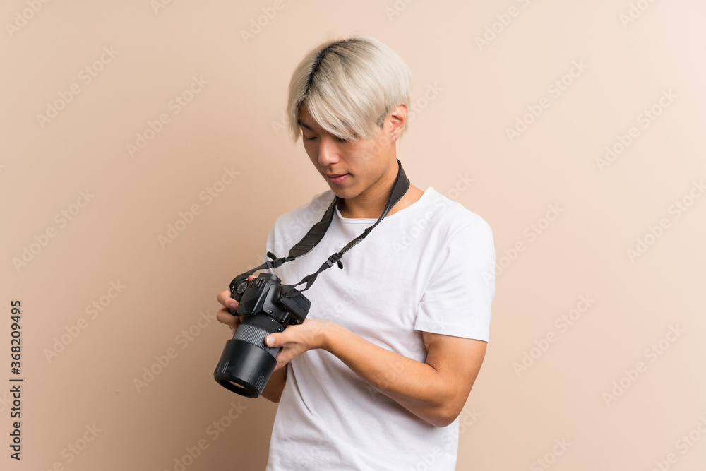 Fototapeta premium Young asian man over isolated background with a professional camera