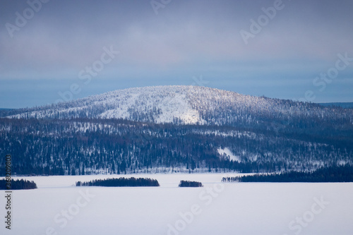 A huge forest covered fell and a frozen lake with some small lakes in Northern Finland. 