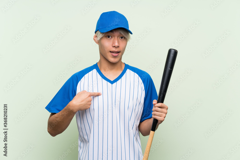 Young asian man playing baseball over isolated green background with surprise facial expression Young asian man playing baseball over isolated green background with surprise facial expression