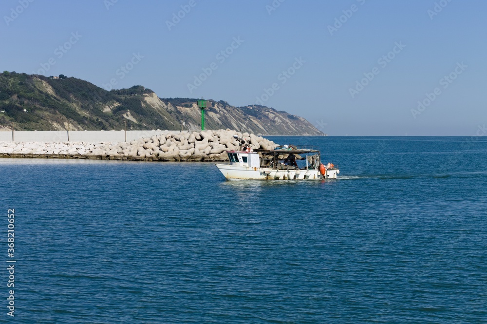 A fishing boat is entering the port in the Mediterranean sea (Pesaro, Italy, Europe)