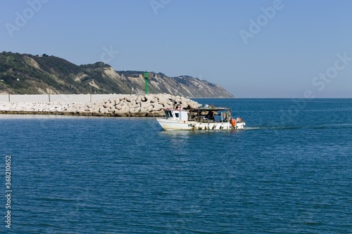 A fishing boat is entering the port in the Mediterranean sea (Pesaro, Italy, Europe)