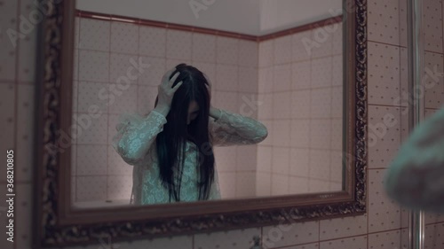 Zombie woman in front of mirror, demonic possession in haunted hotel, evil