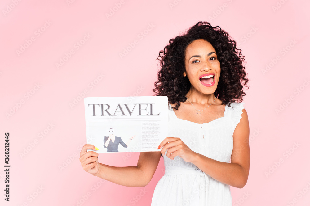 excited african american girl holding travel newspaper isolated on pink excited african american girl holding travel newspaper isolated on pink
