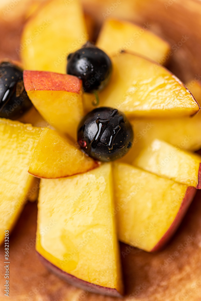 Tasty breakfast. Pancake with peaches and blueberries. Top view.
Tasty breakfast. Pancake with peaches and blueberries. Top view.