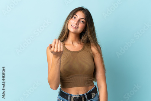 Young caucasian woman isolated on blue background inviting to come with hand. Happy that you came © luismolinero