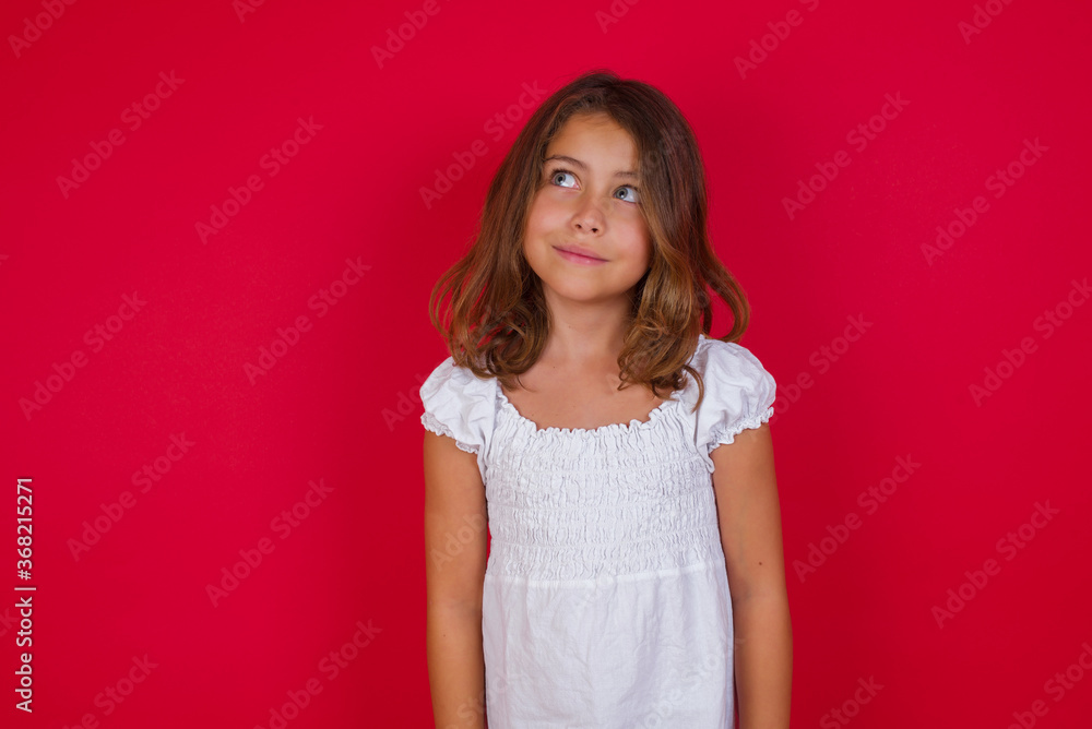 Photo of cheerful positive Little caucasian girl with blue eyes wearing white dress standing over isolated red background looking aside into empty space thoughtful isolated over yellow background Photo of cheerful positive Little caucasian girl with blue eyes wearing white dress standing over isolated red background looking aside into empty space thoughtful isolated over yellow background