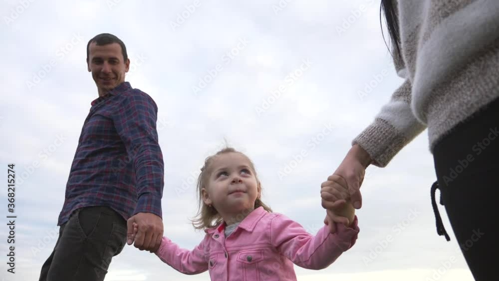 A happy family walks in the Park under the rays of the sun at sunset. Mom, dad and baby holding hands walk in the fresh air, lead a healthy lifestyle. A happy family walks in the Park under the rays of the sun at sunset. Mom, dad and baby holding hands walk in the fresh air, lead a healthy lifestyle.