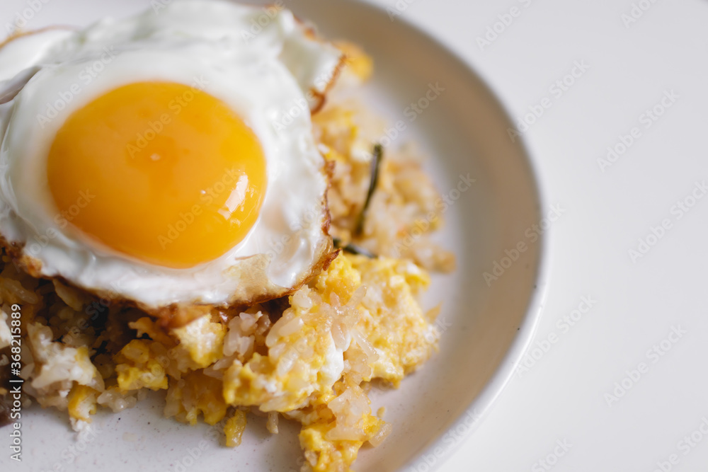 Homemade fried rice with fried egg on top served on white dish. Homemade fried rice with fried egg on top served on white dish.