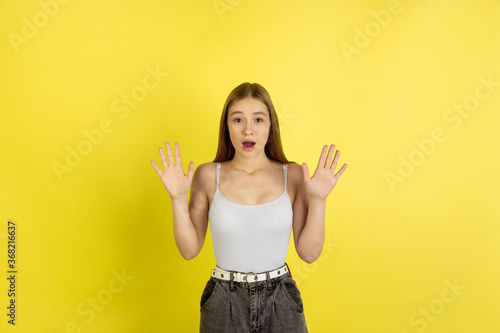 Surprising. Caucasian young girl's portrait isolated on yellow studio background. Beautiful female blonde model. Concept of human emotions, facial expression, sales, ad, youth culture. Copyspace.