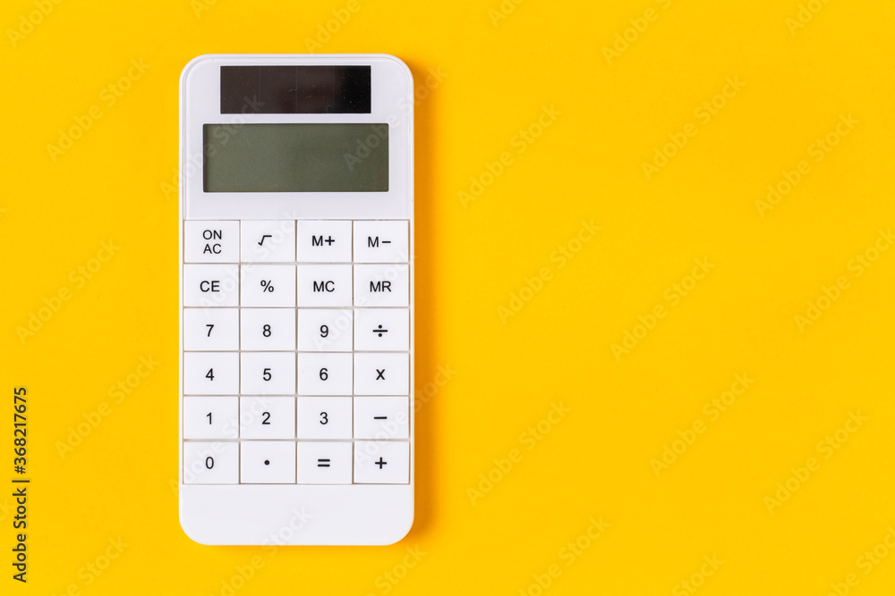 White calculator on yellow background White calculator on yellow background