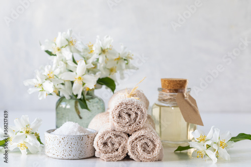 Spa concept of jasmine oil, with bath salt and flowers on a white background. Spa and wellness still life. Copy space.