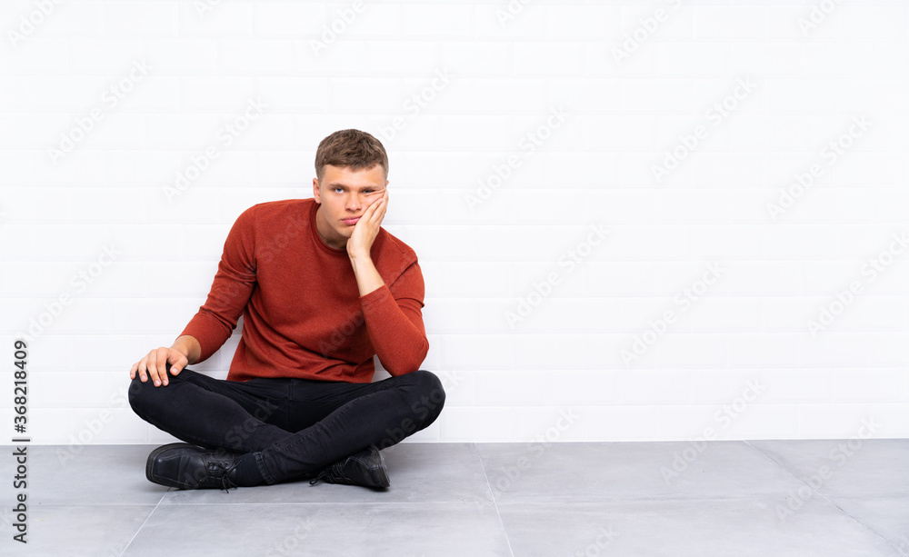 Young handsome man sitting on the floor unhappy and frustrated Young handsome man sitting on the floor unhappy and frustrated