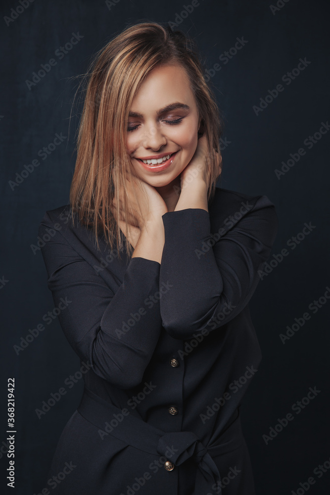 girls with short blonde hair with closed eyes in a dark blue dress holds hands on the neck girls with short blonde hair with closed eyes in a dark blue dress holds hands on the neck