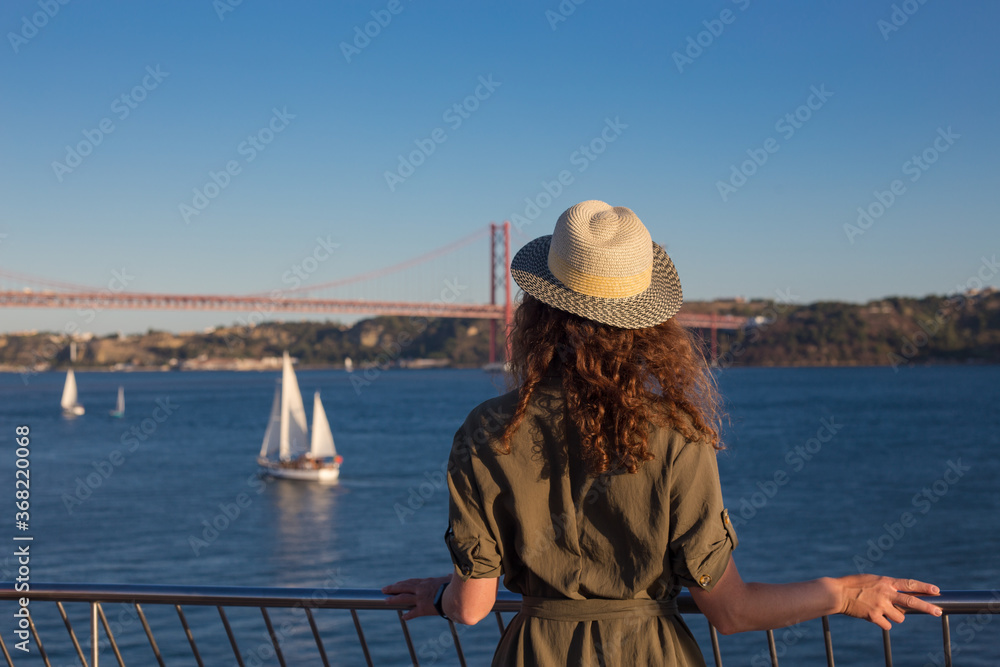 Young woman looking at bridge Ponte 25 de Abril Lisbon