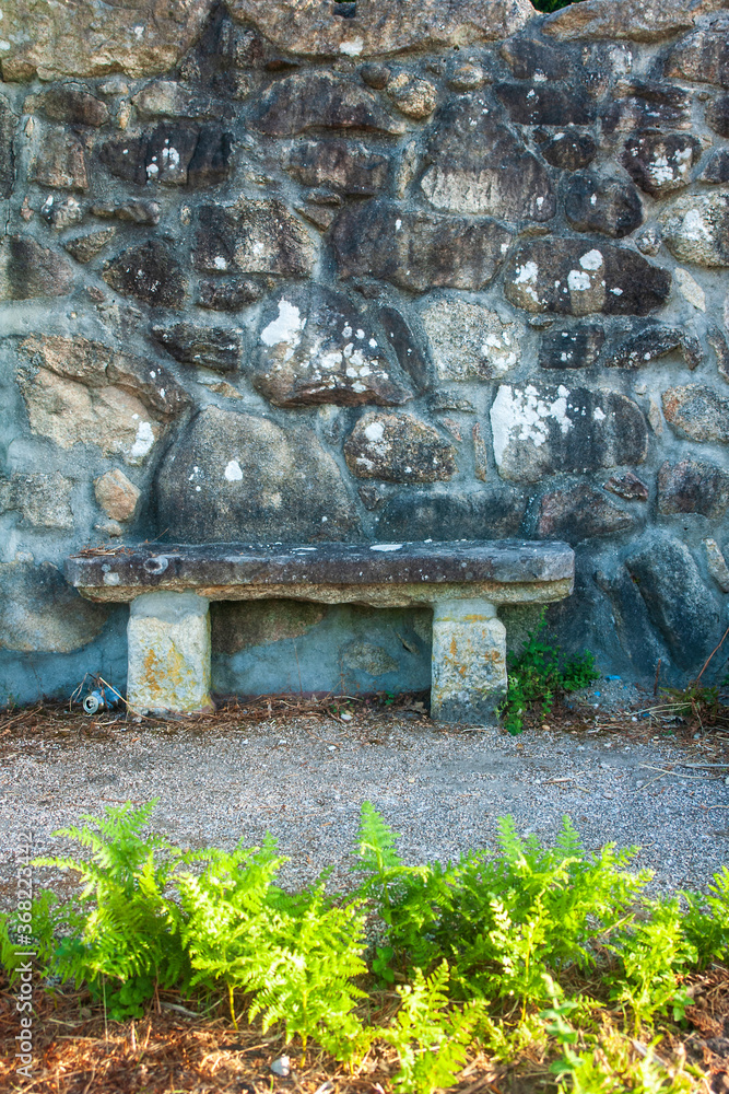 Un banco de piedra junto a un viejo muro en un pueblo gallego