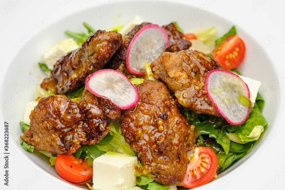 Grilled beef in a sauce with Dejon mustard and soft cheese in a case plate on a gray background.