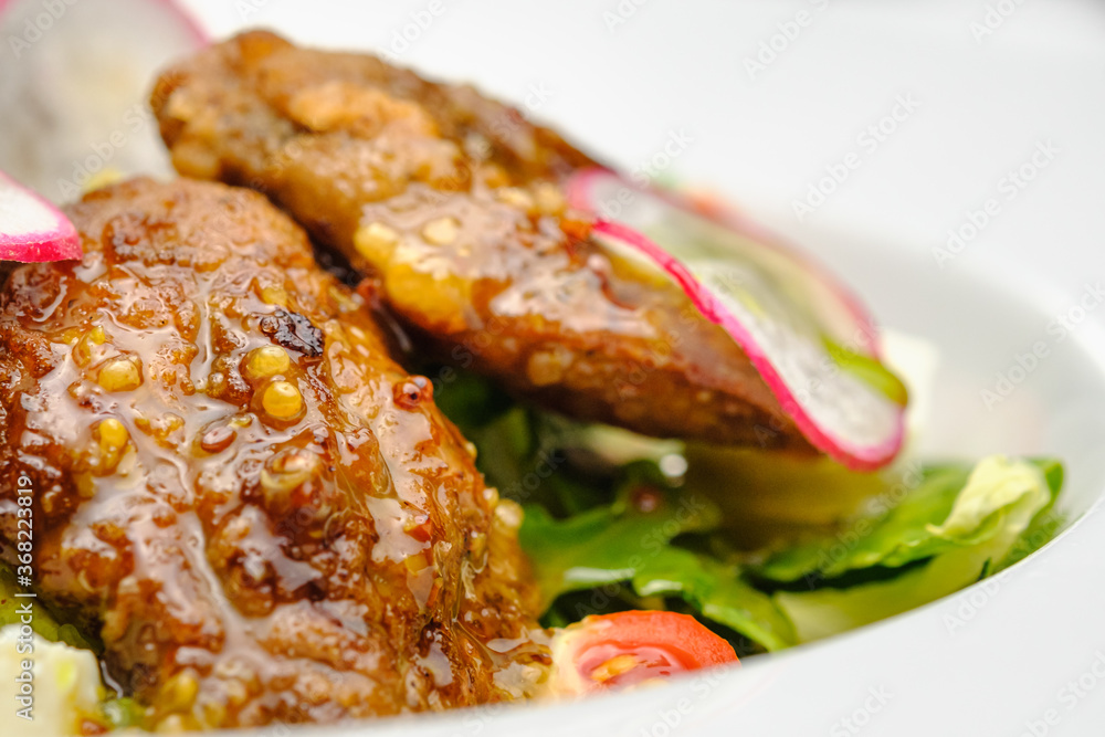 Grilled beef in a sauce with Dejon mustard and soft cheese in a case plate on a gray background. Grilled beef in a sauce with Dejon mustard and soft cheese in a case plate on a gray background.