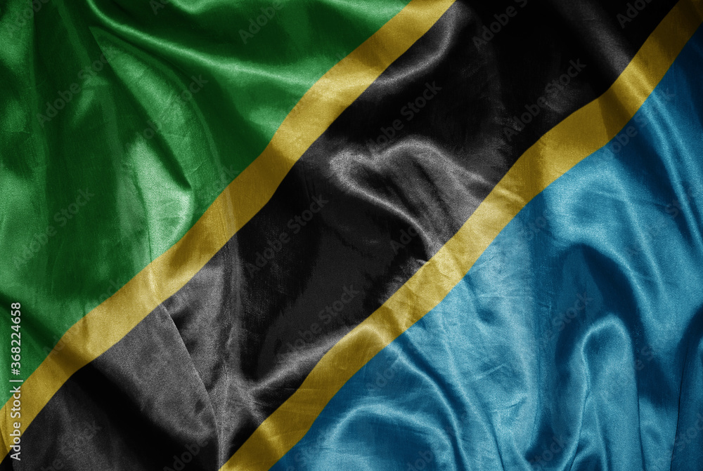 colorful shining big national flag of tanzania on a silky texture