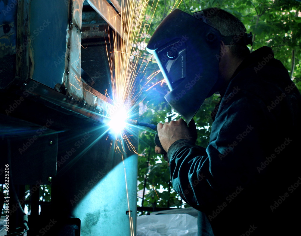 Welder welds metal on machine with sparks Welder welds metal on machine with sparks