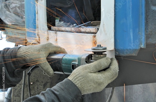 Worker cuts car metal by angular grinding machine