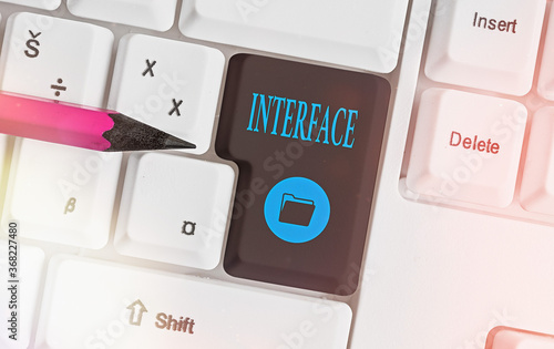 Text sign showing Interface. Business photo showcasing the means by which interaction or communication is achieved Different colored keyboard key with accessories arranged on empty copy space photo