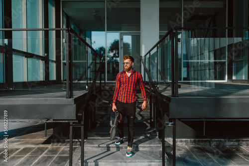 Wallpaper Mural A handsome young bearded caucasian businessman with sunglasses in front of the company, holding an electric scooter in his hand Torontodigital.ca