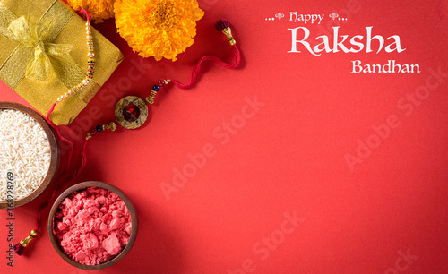 Raksha Bandhan, Indian festival with beautiful Rakhi and  Rice Grains on red background.  A traditional Indian wrist band which is a symbol of love between Sisters and Brothers. photo