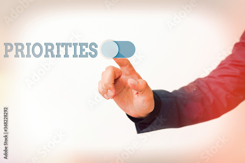Writing note showing Priorities. Business concept for fact or condition of being regarded or treated as more important Model with pointing hand finger symbolizing navigation progress growth