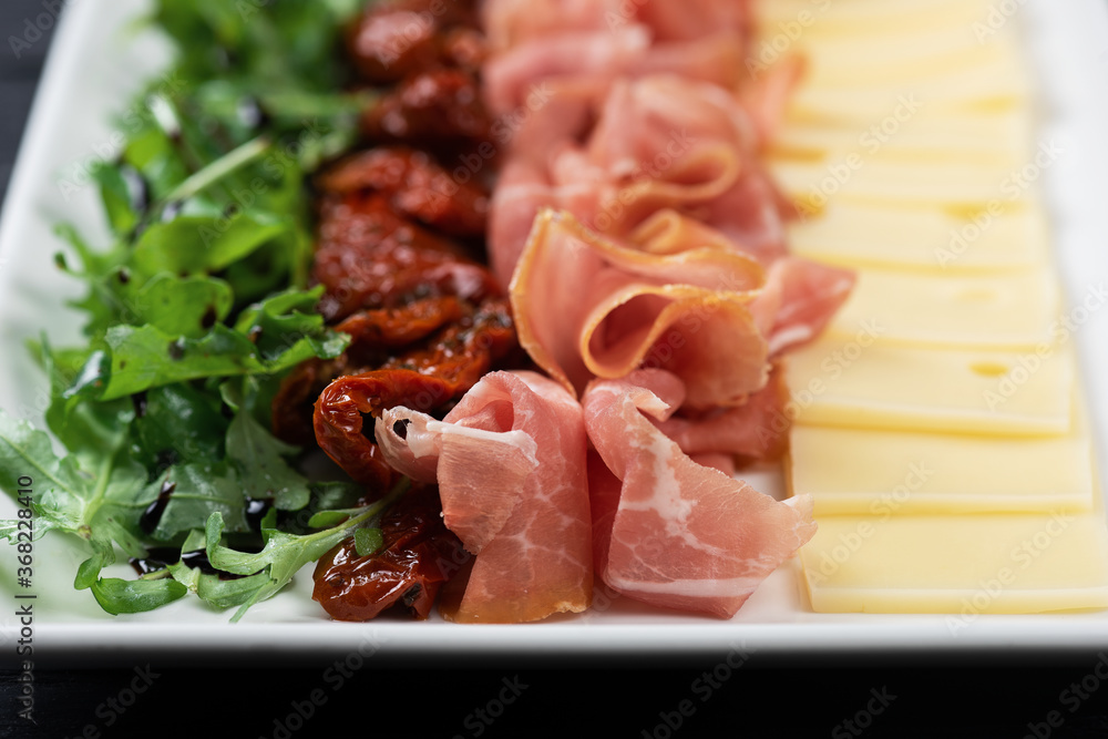 Plate with prosciutto cheese and sun-dried tomatoes Plate with prosciutto cheese and sun-dried tomatoes